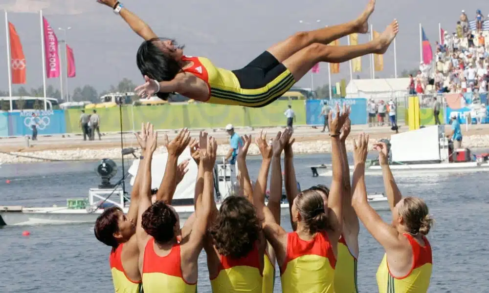 Elisabeta Lipa Oleniuc sendo jogada para cima por sua equipe romena após medalha no remo em Atenas 2004 (Reprodução)