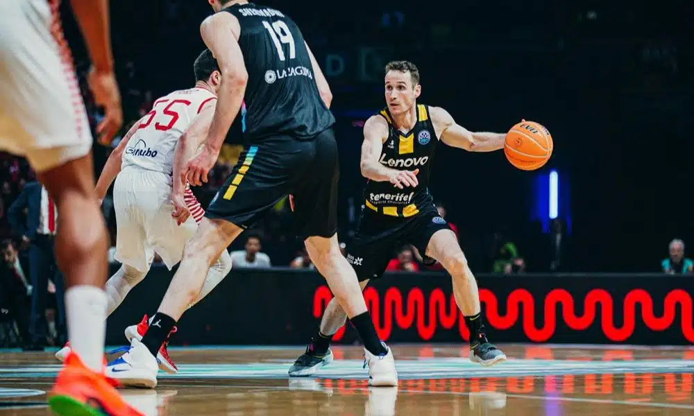 Marcelinho Huertas conduz a bola com a mão esquerda. Ele veste o uniforme preto da equipe do Tenerife. Jogo da final da Champions League de Basquete