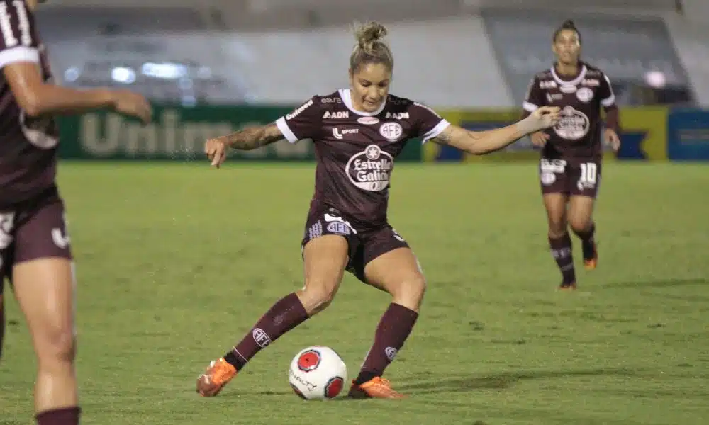 Laryh, vestindo o uniforme todo grená da Ferroviária, passa a bola