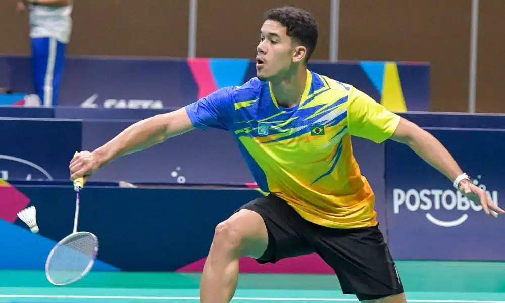 Brasil no badminton: Jonathan Mathias se estica para rebater a peteca. Ele veste shorts preto e camisa amarela com detalhes em azul