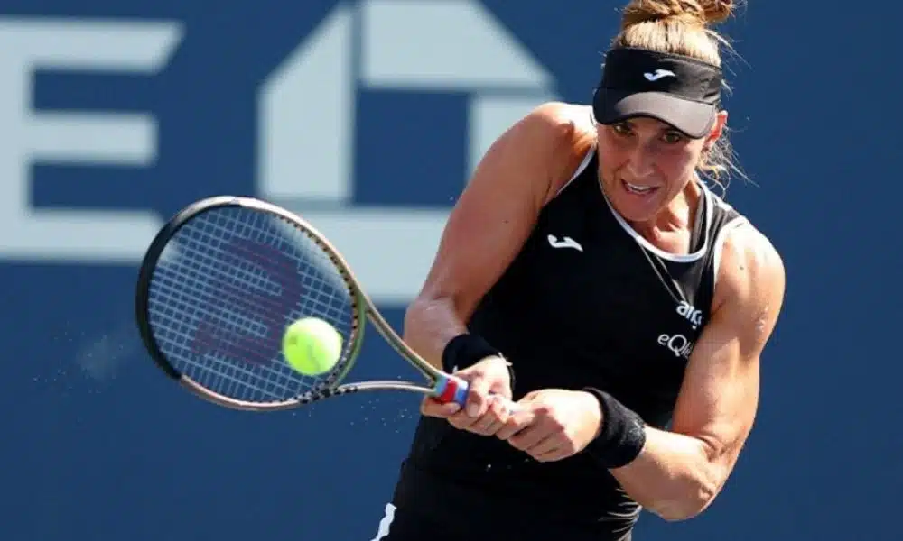 WTA 1000 de Guadalajara: Bia Haddad Maia manda uma devolução segurando a raquete com as duas mãoes. Ela veste regata e viseira preta