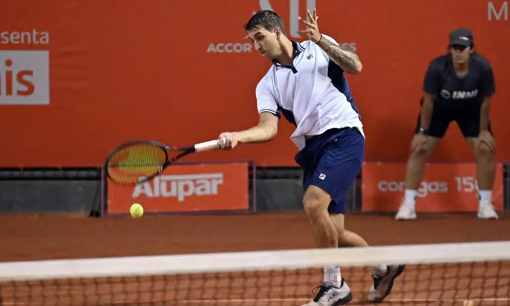 Felipe Meligeni Alves ataca bola com um forehand de direita. Ele veste bermuda azul e camisa branca