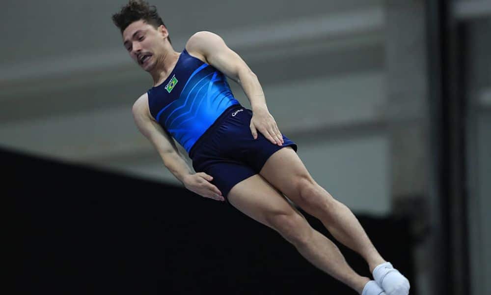 Rayan e Camila Lopes na Inglaterra - Rayan Castro veste uniforme azul da seleção. Ele faz uma salto na posição esticada / Rayan Castro Copa do Mundo de Ginástica de Trampolim Baku