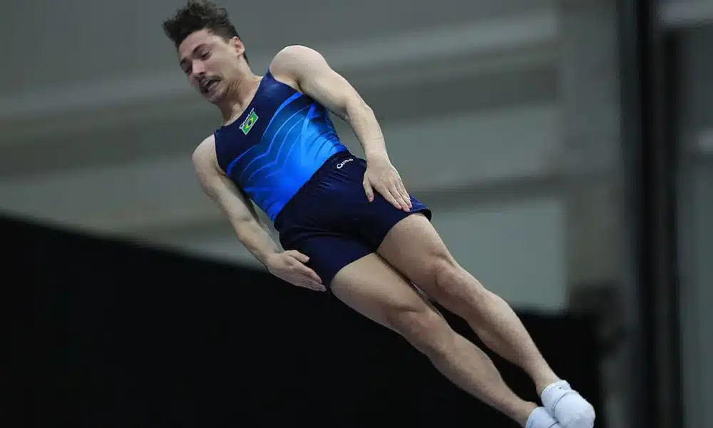 Rayan e Camila Lopes na Inglaterra - Rayan Castro veste uniforme azul da seleção. Ele faz uma salto na posição esticada / Rayan Castro Copa do Mundo de Ginástica de Trampolim Baku