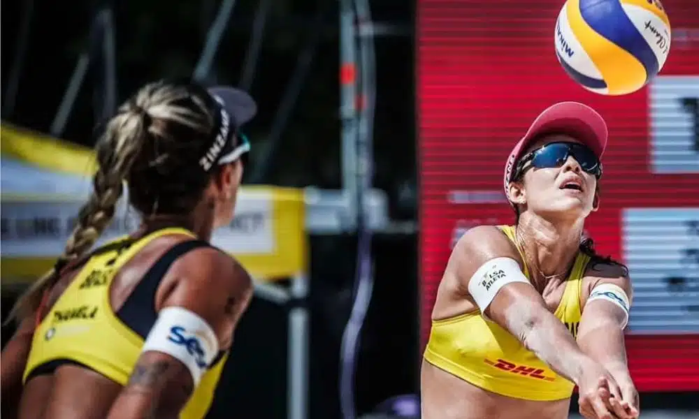 Talita faz manchete enquanto Thâmela observa. Ambas vestem top amarelo, bonés e óculos escuros