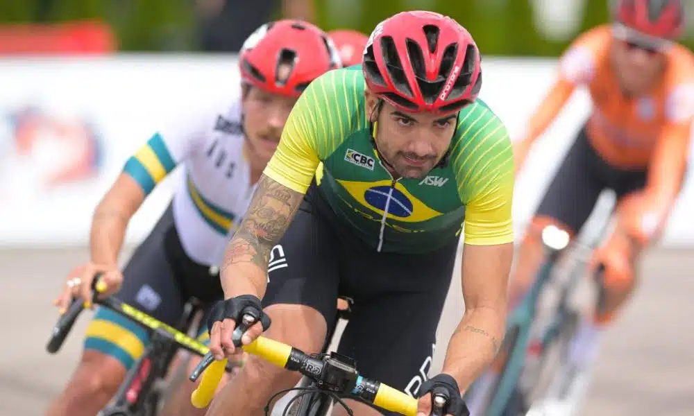 Brasil no ciclismo paralímpico - Lauro Chaman durante prova de estrada. Ele veste umca camisa verde com a bandeira do Brasil e um capacete vermelho Paris 2024 mundial de paraciclismo