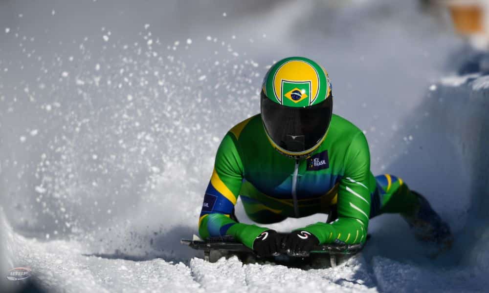 Nicole Silveira deitada no trenó. Ela usa os pés para frear ao final da pista