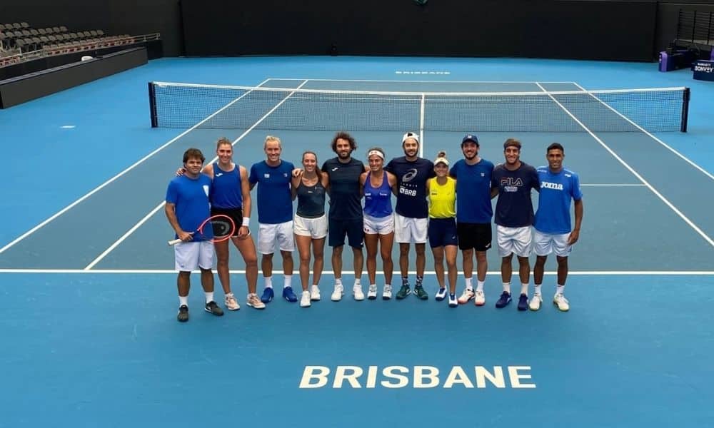 Equipe do Brasil na United Cup. Todos estão enfileirados sobre quadra azul, com o nome de Brisbane pintado em branco Bia Haddad e Felipe Meligeni ao vivo
