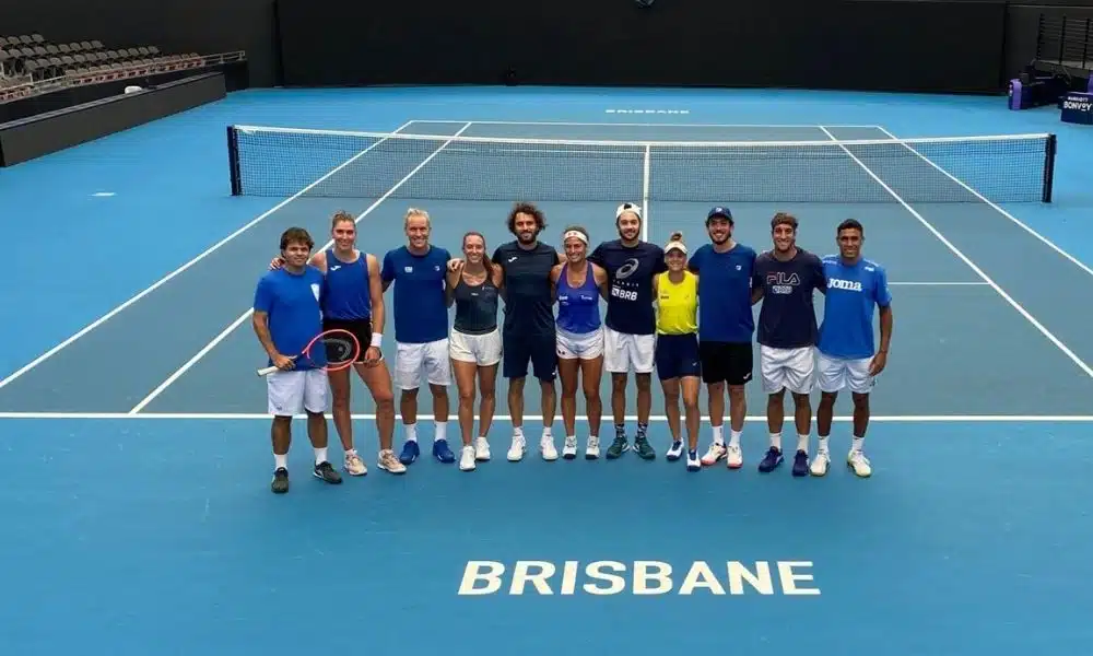 Equipe do Brasil na United Cup. Todos estão enfileirados sobre quadra azul, com o nome de Brisbane pintado em branco Bia Haddad e Felipe Meligeni ao vivo