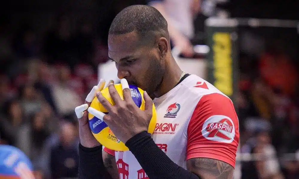 Yoandy Leal, usando o uniforme branco e vermelho do Piacenza, beija uma bola de vôlei