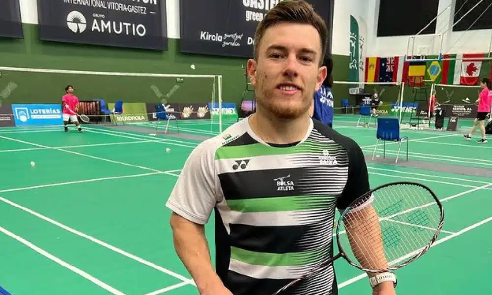 Vitor Tavares parabadminton - Vitor segura sua raquete em frente a uma quadra verde