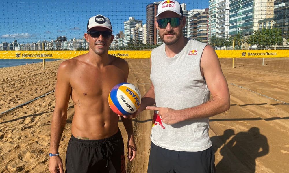 Mas Alisson e Oscar posam para foto na areia. Por fim, eles estão em frente à uma rede de vôlei de praia. Enquanto isso
