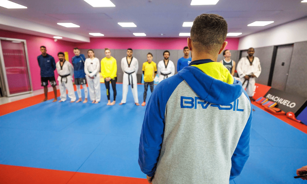 Treinador e atletas de taekwondo enquanto treinam na base do COB