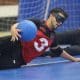 Mas - Regional Nordeste de Goalball. O pivô Renan, da Apace, joga o corpo para o lado esquerdo e se apoia sobre o braço para defender, enquanto abraça a bola com a mão direita