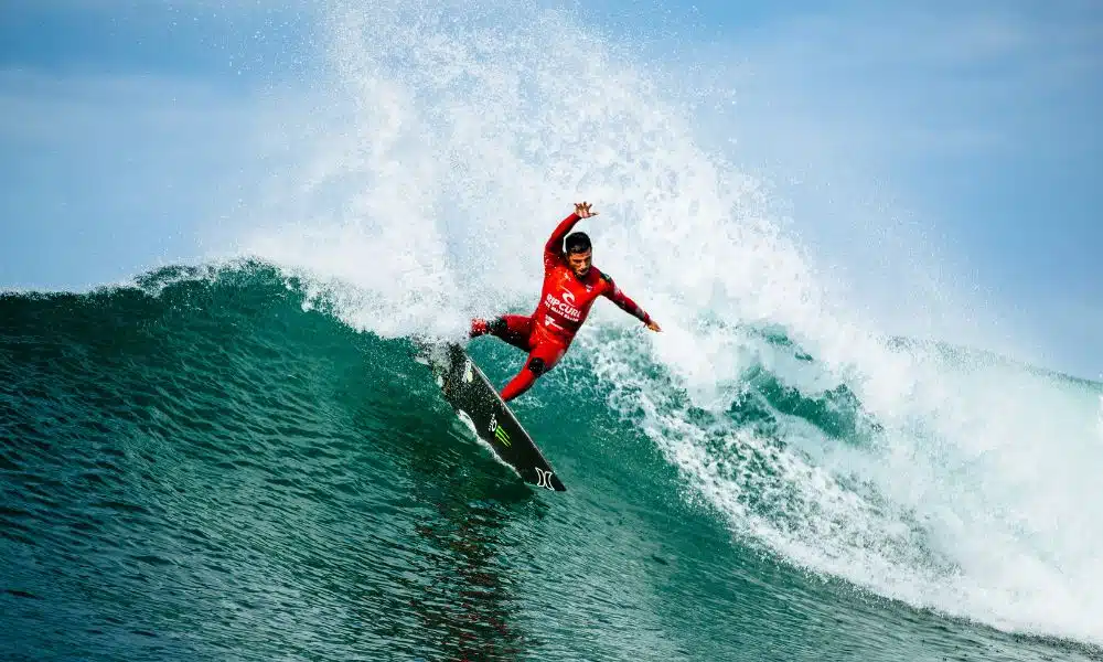 Mas - WSL em Bells Beach. Filipe Toledo surfa numa onda. Ele veste uma lycra vermelha mas