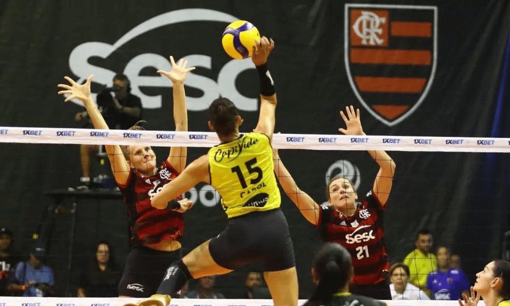 Praia Clube x Sesc Flamengo na superliga feminina. Carolana ataca enquanto rubro-negras tentam defender. Jogo ao vivo no SporTV
