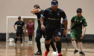 Dudu, que é preto e usa cabelo raspado em curto, conduz a bola, que está dominada em seu pé esquerdo. Ele veste uniforme preto com detalhes em azul, do INV (Renan Cacioli/ CBDV)