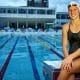 Na imagem, Graciele Herrmann sentada no bloco de partida da piscina.
