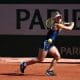 Na imagem, Laura Pigossi rebatendo a bolinha com sua raquete, em um golpe de backhand.
