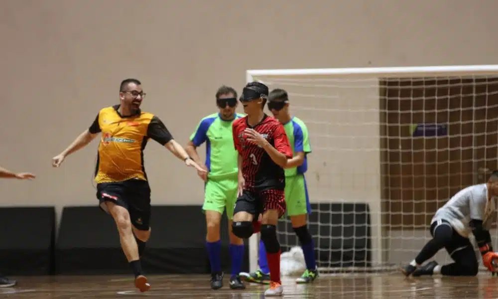 Samir corre em direção ao centro da quadra enquanto o chamador Taffarel corre em sua direção para comemorar o gol da Apadv. Ao fundo, goleiro da Acergs está se levantando / Regional Sul-Sudeste de Futebol de Cegos