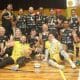 Equipe da Agafuc posa para foto. Os atletas têm medalhas de ouro no pescoço, enquanto a taça está no chão ao centro