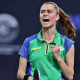 Bruna Takahashi ergue o braço para comemorar um ponto em jogo do Mundial de tênis de mesa. Ela veste uma camiseta verde com mangas azuis e tem o cabelo preso em um rabo de cavalo.