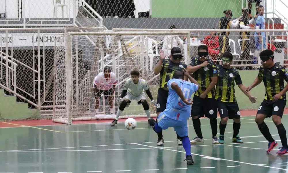 Selmi, da ADVP, chuta de pé esquerdo, a bola vai passando pelo lado da barreira com três atletas da Uniace e, ao fundo, o goleiro Igor aguarda a trajetória da bola com os olhos bem atentos ao lance (Renan Cacioli/CBDV)
