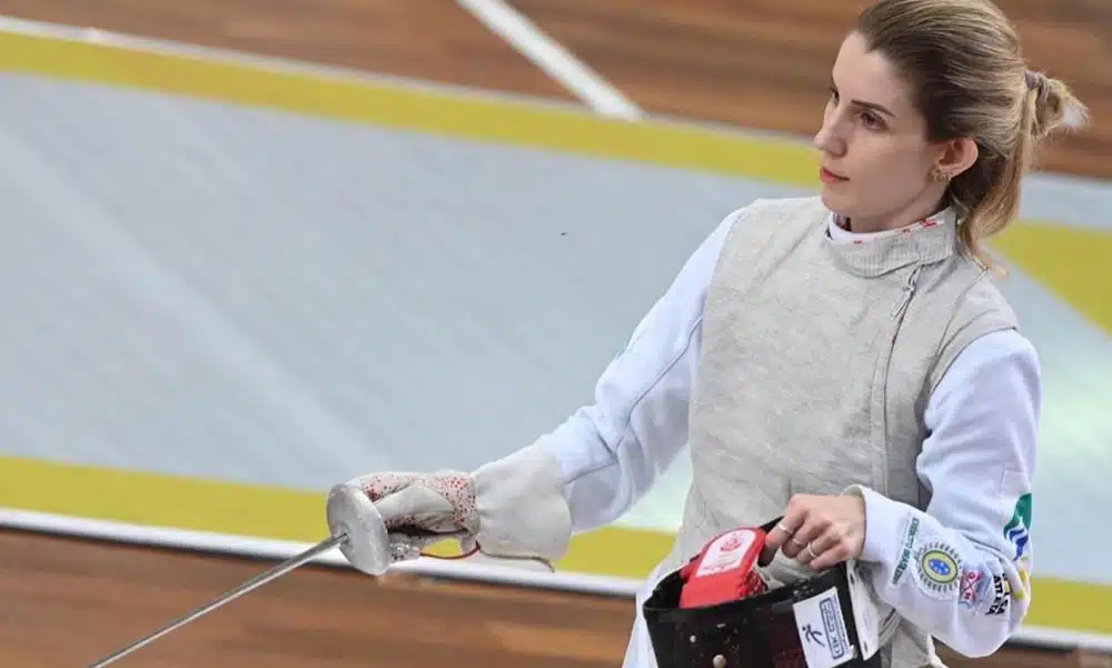Na imagem, Mariana Pistoia com o florete na mão e a capacete de proteção na outra.