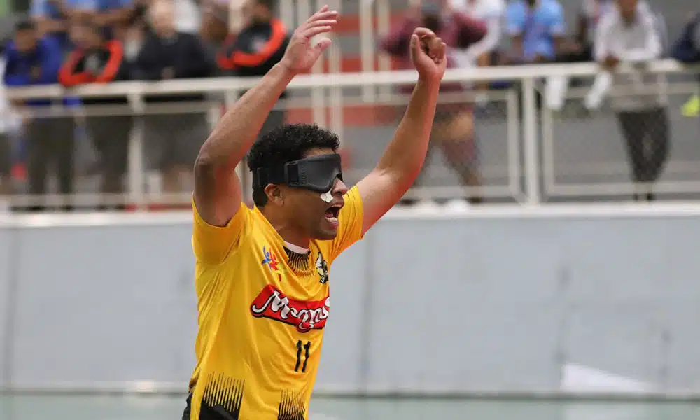 Na imagem, Leandro Moreno ergue os braços na comemoração de seu gol. Ele veste camisa amarela com detalhes em preto da Uniace.