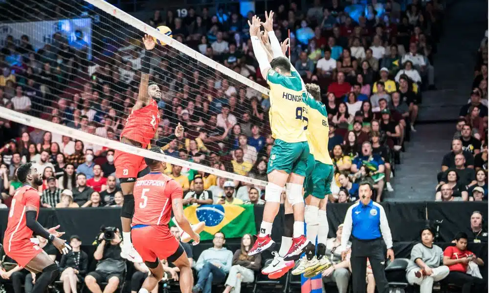 Jogador de Cuba ataca enquanto atletas do Brasil tentam bloquear em jogo da Liga das Nações de Vôlei Masculino VNL