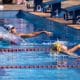 Na imagem, momento de duas atletas largando na piscina para disputar a prova.