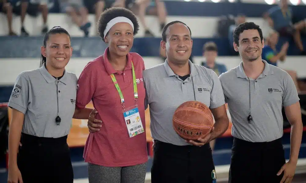 Janeth Arcain ao lado de ábtiras de um jogo de basquete