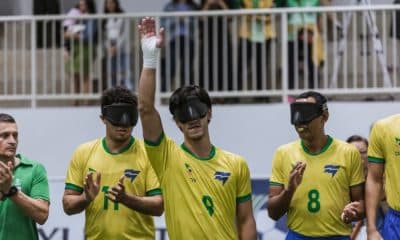 Tiago Paraná ergue o braço direito para saudar o público antes de início de jogo. Ele está perfilado ao lado de Edson, Jardiel e Nonato, que aparecem na imagem