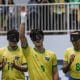 Tiago Paraná ergue o braço direito para saudar o público antes de início de jogo. Ele está perfilado ao lado de Edson, Jardiel e Nonato, que aparecem na imagem