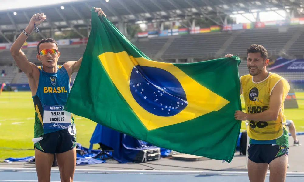 Yeltsin Jacques e atleta-guia Edelson Ávila com bandeira do Brasil no Mundial de atletismo paralímpico