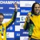 Na imagem, Douglas Matera e Carol Santiago mostrando suas medalhas no pódio.