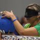 Carol Duarte, do Brasil, está próxima da trave, de costas para a quadra adversária, antes de iniciar seu movimento de arremesso. Ela veste camisa de mangas curtas amarela com detalhes em verde da Seleção e usa esparadrapos nas pontas de alguns dedos das duas mãos.