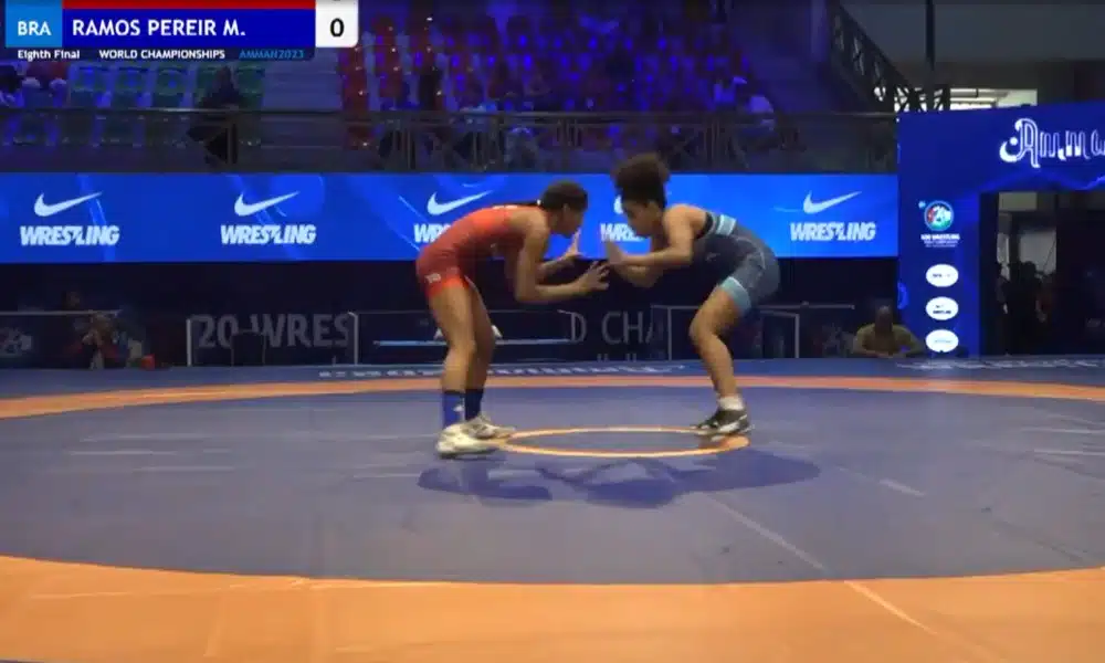 Mayara Ramos, que está à direita da imagem e veste traje azul, luta contra rival na estreia do Mundial Sub-20 de Wrestlig