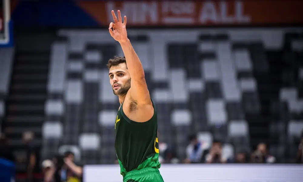 Raulzinho ergue os braços e faz o sinal de três com a mão em jogo do Brasil na Copa do Mundo de basquete
