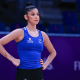 Duda Arakaki no Mundial de Ginástica Rítmica. A ginasta está ao lado do tapete vendo as colegas do conjunto no treino de pódio