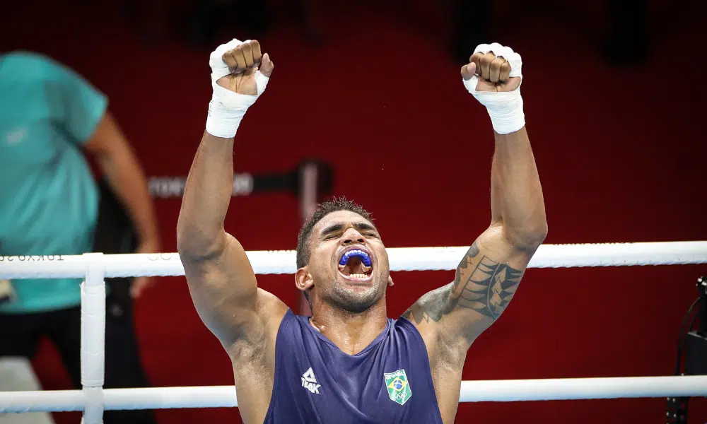 Abner Teixeira ergue os braços em comemoração após vitória no boxe