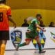 Na imagem, o ala Léo, da Agafuc, que veste uniforme predominantemente verde, sai vibrando após marcar seu gol entre dois adversários do CFCP, que usam camisa laranja.