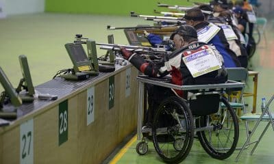 Na imagem, paratleta do Brasil em posição de disparo, com outros atletas ao lado.