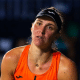 Bia Haddad Maia, usando laranja e viseira, faz cara de lamentação durante o WTA 1000 de Pequim
