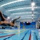 Na imagem, nadador do Brasil pulando na piscina, em um dos cinco esportes aquáticos.