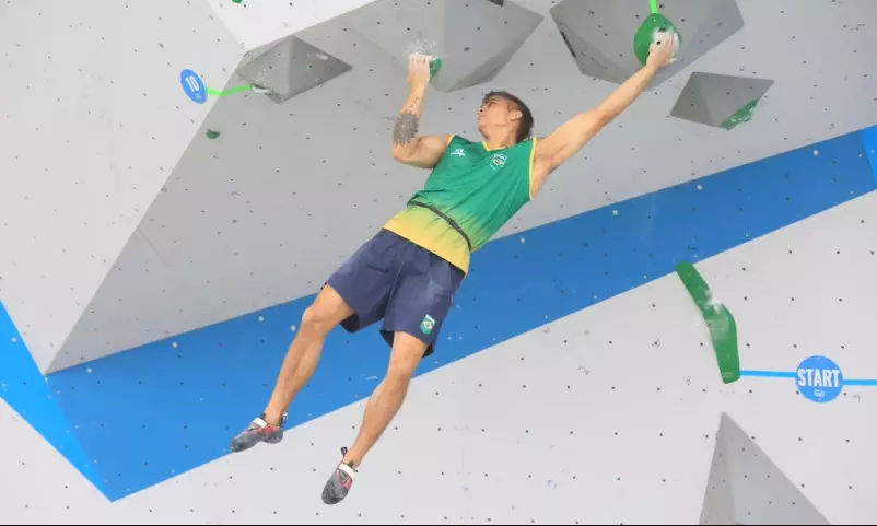 Na imagem, Felipe Ho pendurado na parede entre obstáculos.