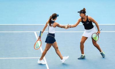 Luisa Stefani e Ingrid Martins se cumprimentam, uma com a raquete em cada mão, sobre a quadra dura do WTA 1000 de Pequim