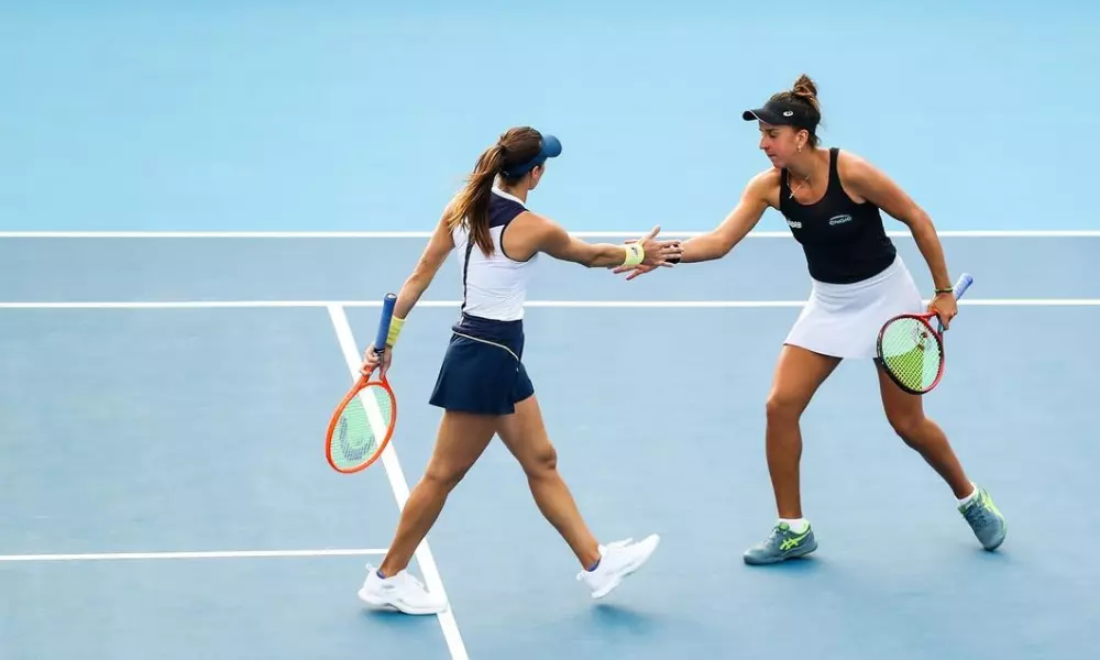 Luisa Stefani e Ingrid Martins se cumprimentam, uma com a raquete em cada mão, sobre a quadra dura do WTA 1000 de Pequim