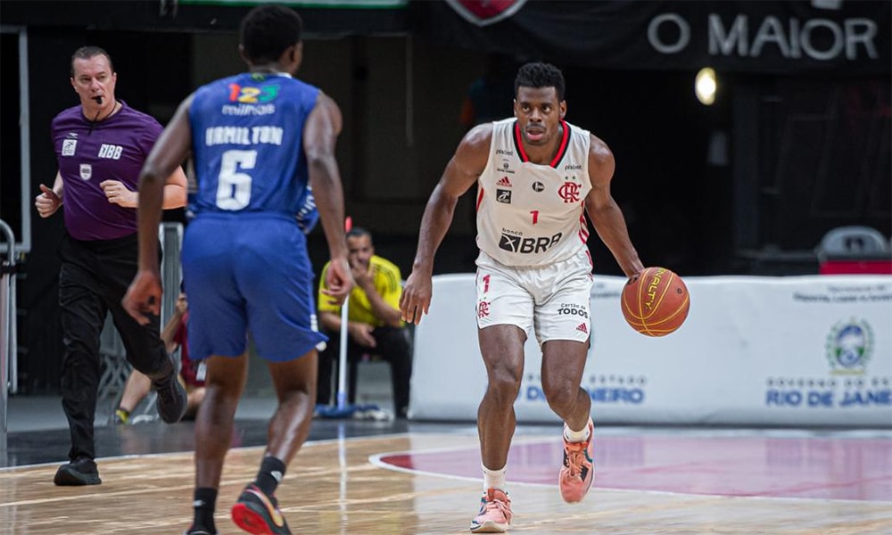 Na imagem, atleta do Flamengo armando a jogada enquanto o marcador do Minas cerca.