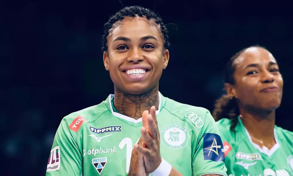 Bruna de Paula sorri e bate palmas; ela está com a camisa do Gyori durante partida da Champions League de handebol feminino com o time de Gabi Moreschi